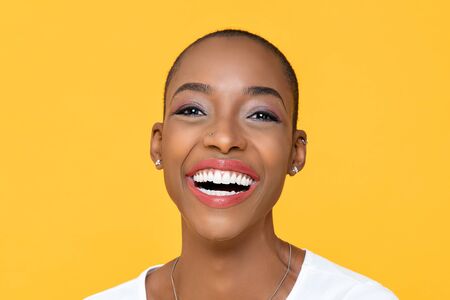 Close up portrait of friendly happy African American woman smiling on isolated colorful yellow backgroundの写真素材