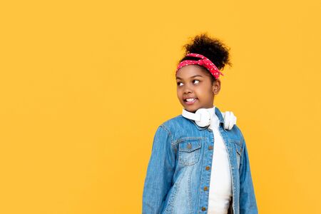 Smiling fashionable mixed raced African girl looking at copy space aside studio shot isolateded on colorful yellow backgroundの写真素材