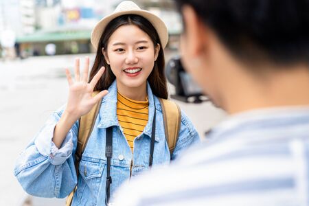 Smiling beautiful Asian woman tourist travel vlogger say hi to camera in the cityの写真素材