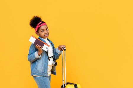 Traveling African American girl wih baggage passport and boarding pass isolated on yellow background with copy spaceの写真素材