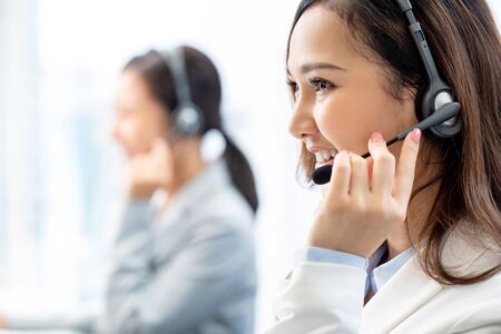 Smiling telemarketing Asian woman working in call center officeの写真素材