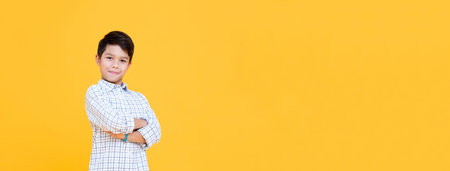 Happy smiling boy with arm crossed gesture isolated on yellow banner background with copy space