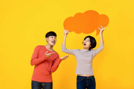 Young Asian college student friends in casual clothes with speech bubble on colorful yellow studio background