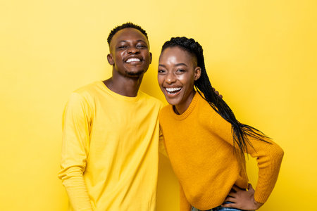 Smiling young African American couple in yellow isolated studio background