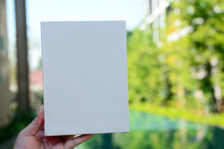 Hand holds white sheet on backgroundの写真素材