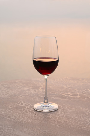 Glass of wine at sunset on the seaの写真素材