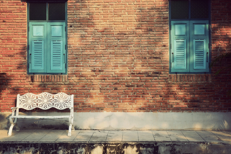 White wooden chair with vintage red brick wall and blue window. Vintage backgroundの写真素材