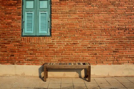 Wooden chair with vintage red brick wall and blue window. Vintage backgroundの写真素材