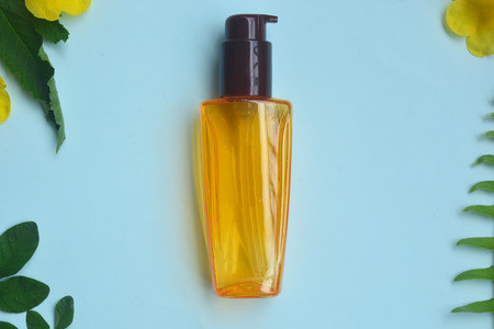Skincare Flat lay Hair serum  isolated on pastel background with green leaf and yellow flower, Minimal makeup fashion concept.の写真素材