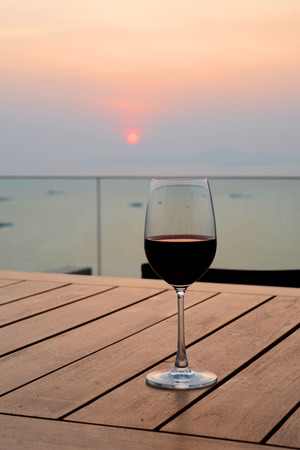 Romantic glass of red wine Standing on the beach at colorful sunset, Glasses of white wine against sunset, white wine on the sky.の写真素材