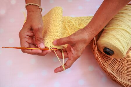 Woman hands knitting crochet yarn. hobby crafts things, Handmade crochet tiny hat from yellow cotton yarn.の写真素材