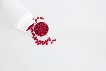 Pills spilling out of pill bottle and isolated on white background. Top view with copy spaceの写真素材