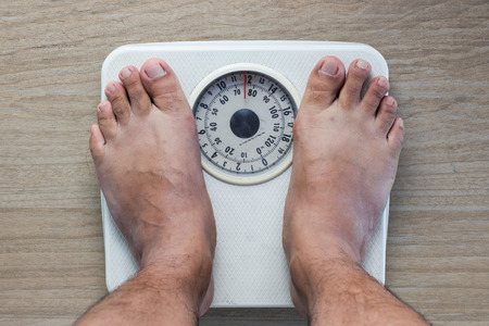 Low section of man standing on weight scaleの写真素材