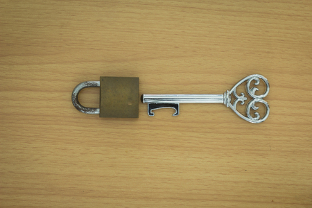 Key with a heart inside and lock on wood backgroundの写真素材