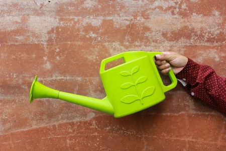 hand holding watering can on stone backgroundの写真素材