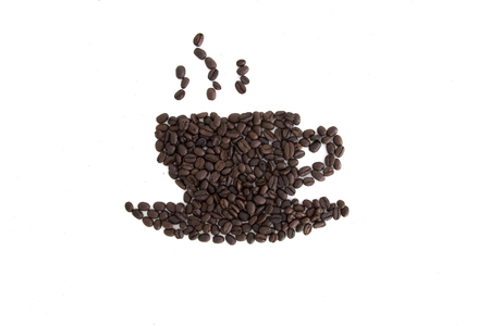 Roasted coffee beans placed in the shape of a cup and saucer on a white surfaceの写真素材