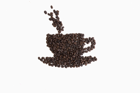 Roasted coffee beans placed in the shape of a cup and saucer on a white surfaceの写真素材
