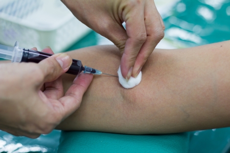 Doctor drawing blood sample from arm for blood testの写真素材