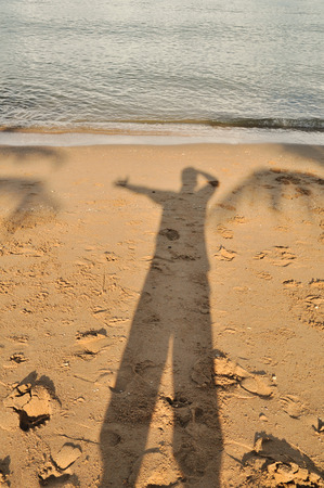 Man's shadow on sand beach : concept feel relax.の写真素材