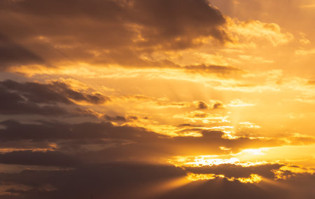 The sun was shining golden yellow through the many clouds in the evening.