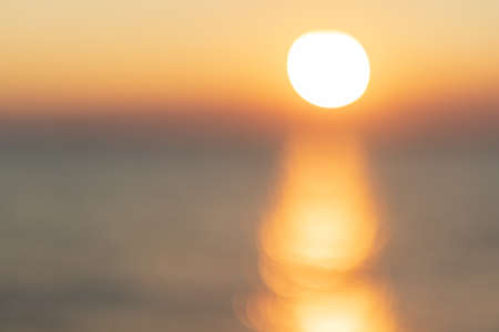 Blurred view of the sea seen with orange-yellow bokeh in the eveningの写真素材