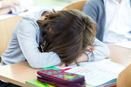 school girl sleeping at her desk during classの写真素材