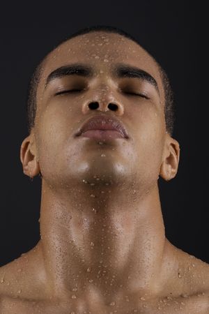 Drops of the water on face of a young man on black background. の写真素材