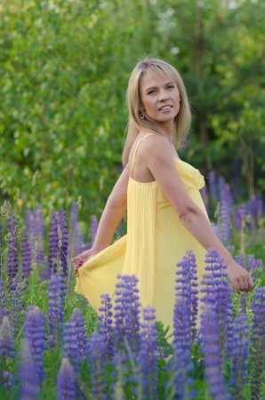 Young beautiful woman in the lupine field の写真素材