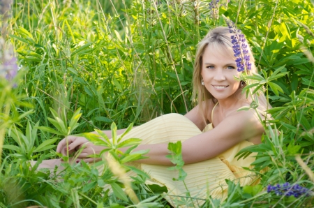 Young beautiful woman in the lupine field の写真素材