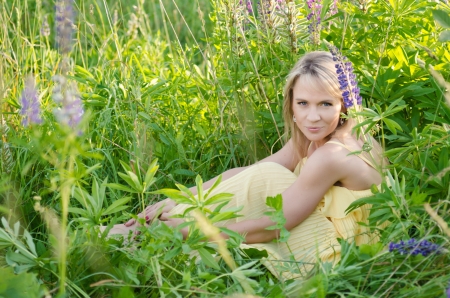 Young beautiful woman in the lupine field の写真素材
