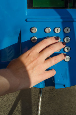 Woman?s hand dialing a telephone