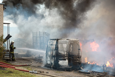 Huge fire of buildings and cars. Firefighters at work.