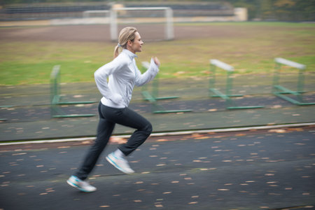 Woman running in the stadium, panning technique, small depth of field