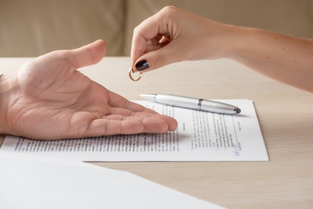 Divorce: hands of wife and husband signing divorce documents, woman returning wedding ringの写真素材