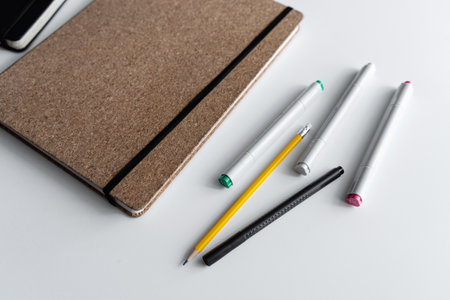 Minimalist notebook and stationery set on a white deskの写真素材
