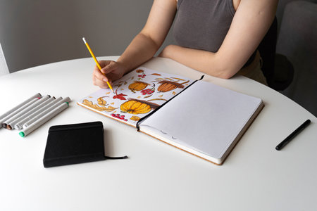 Woman coloring autumn pumpkins illustration at deskの写真素材