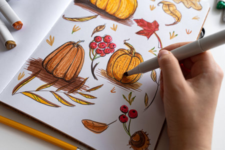 Hand holding marker while drawing autumn illustrationの写真素材