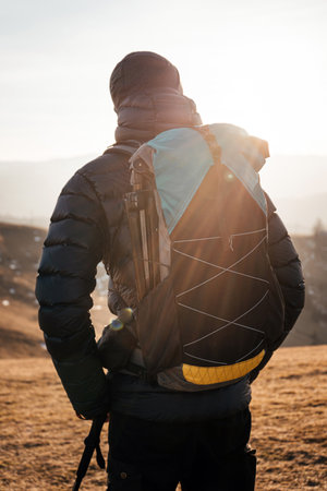 Hiker at sunrise with backpack and trekking polesの写真素材