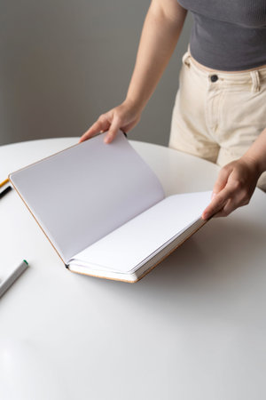 A woman opening a blank sketchbook, symbolizes a fresh start, creativity, and new opportunities. The...