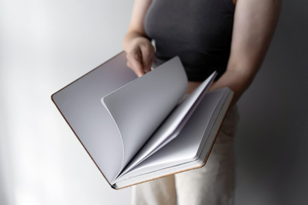 Woman holding pencil over blank notebook by a window. New start conceptの写真素材
