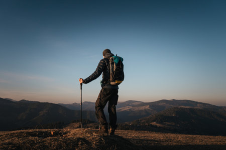 Solo hiker on mountain at sunrise with trekking polesの写真素材