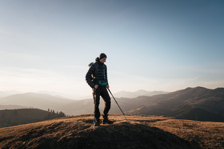 Solo hiker on mountain at sunrise with trekking polesの写真素材