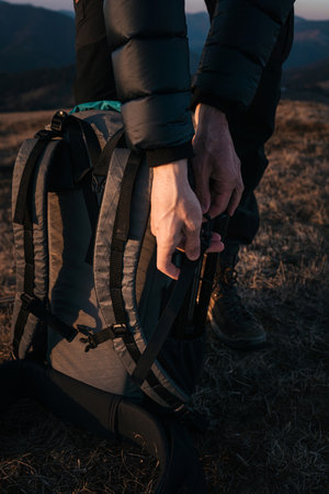 Hiker Packing Gear into Backpack at Duskの写真素材