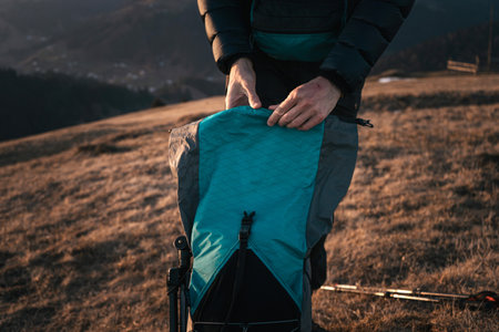 Hiker Packing Gear into Backpack at Duskの写真素材