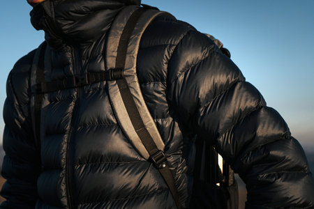 Detailed shot of a hiker's backpack and jacket straps during a hike in the mountains. The image highlights the essential gear needed for a successful outdoor adventure.の写真素材