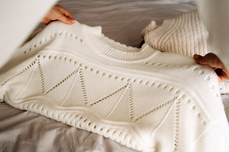 Young Woman Organizing Warm Knitwear on Bed
