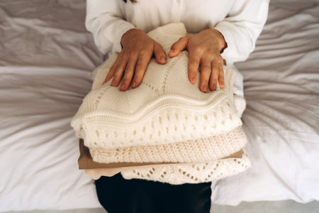 Woman Holding Folded Knit Sweaters in Handsの写真素材