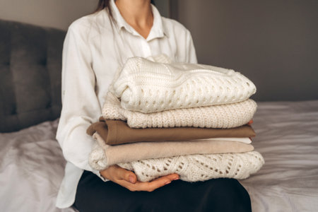 Woman Holding Folded Knit Sweaters in Handsの写真素材