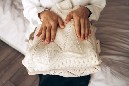 Woman Holding Folded Knit Sweaters in Hands