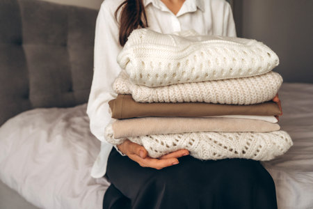Woman Holding Folded Knit Sweaters in Hands